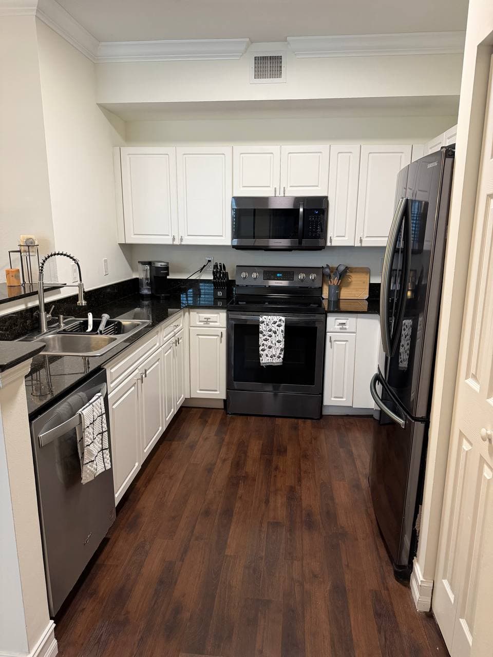 Fully equipped kitchen with white cabinets and black granite countertops